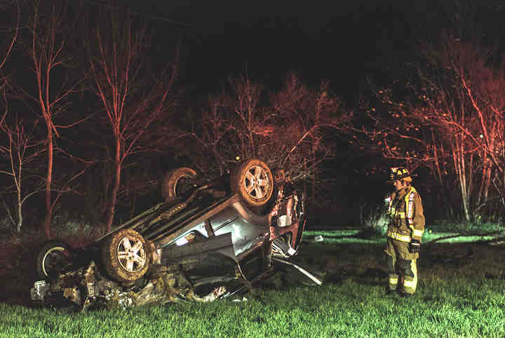 College Township firefighter inspects the scene of a car crash in the 19800 block of Coshocton Road. This vehicle was traveling eastbound, when the driver lost control, went off the road, striking an embankment, hitting a tree, a utility pole and another tree before overturning.   (Joshua Morrison / Freelance)